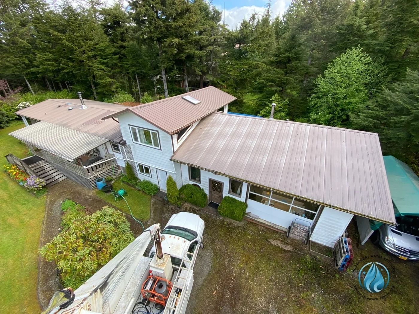 Northwest Water Services soft washing a metal roof from a lift